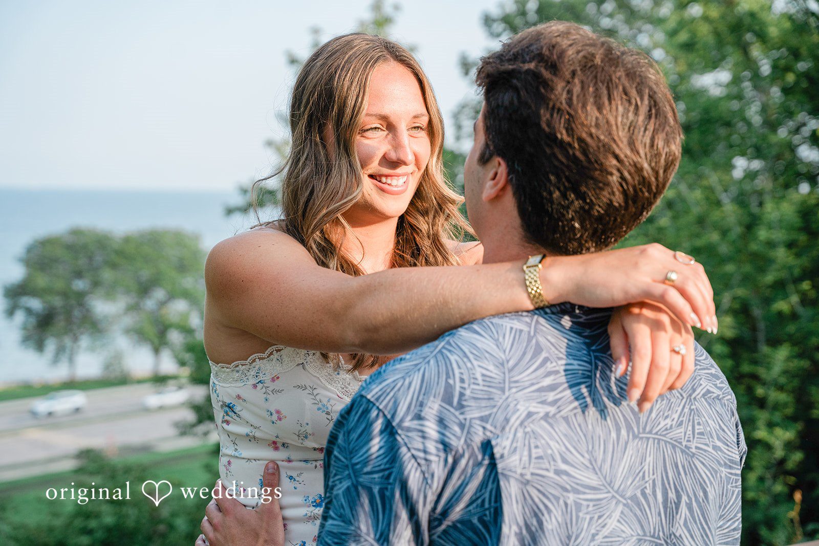 A couple embracing and smiling against a background of water.