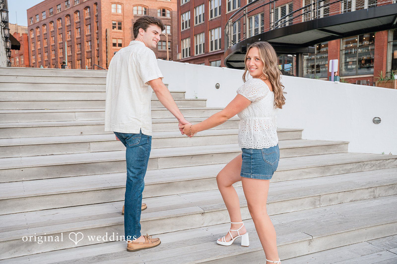 A couple holding hands while walking along a paved path.