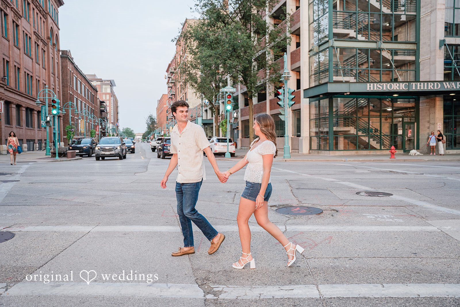 A man and a woman walk hand-in-hand down an empty city street.