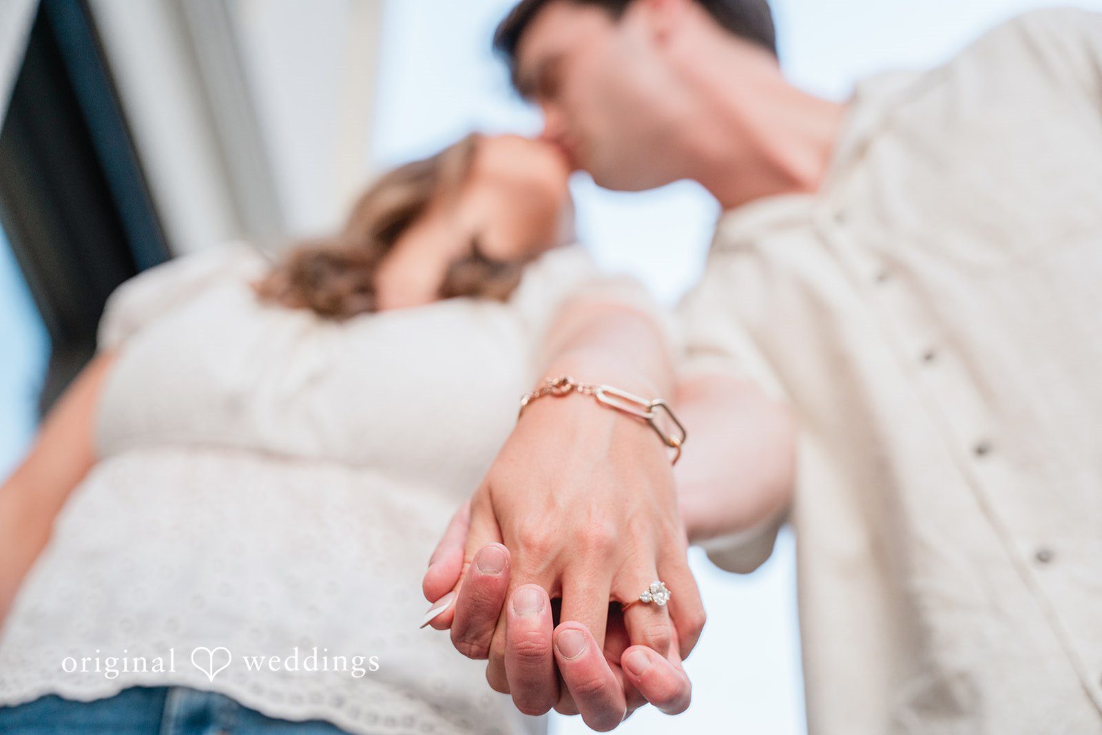 Couple hold hands tightly, captured from a low angle.