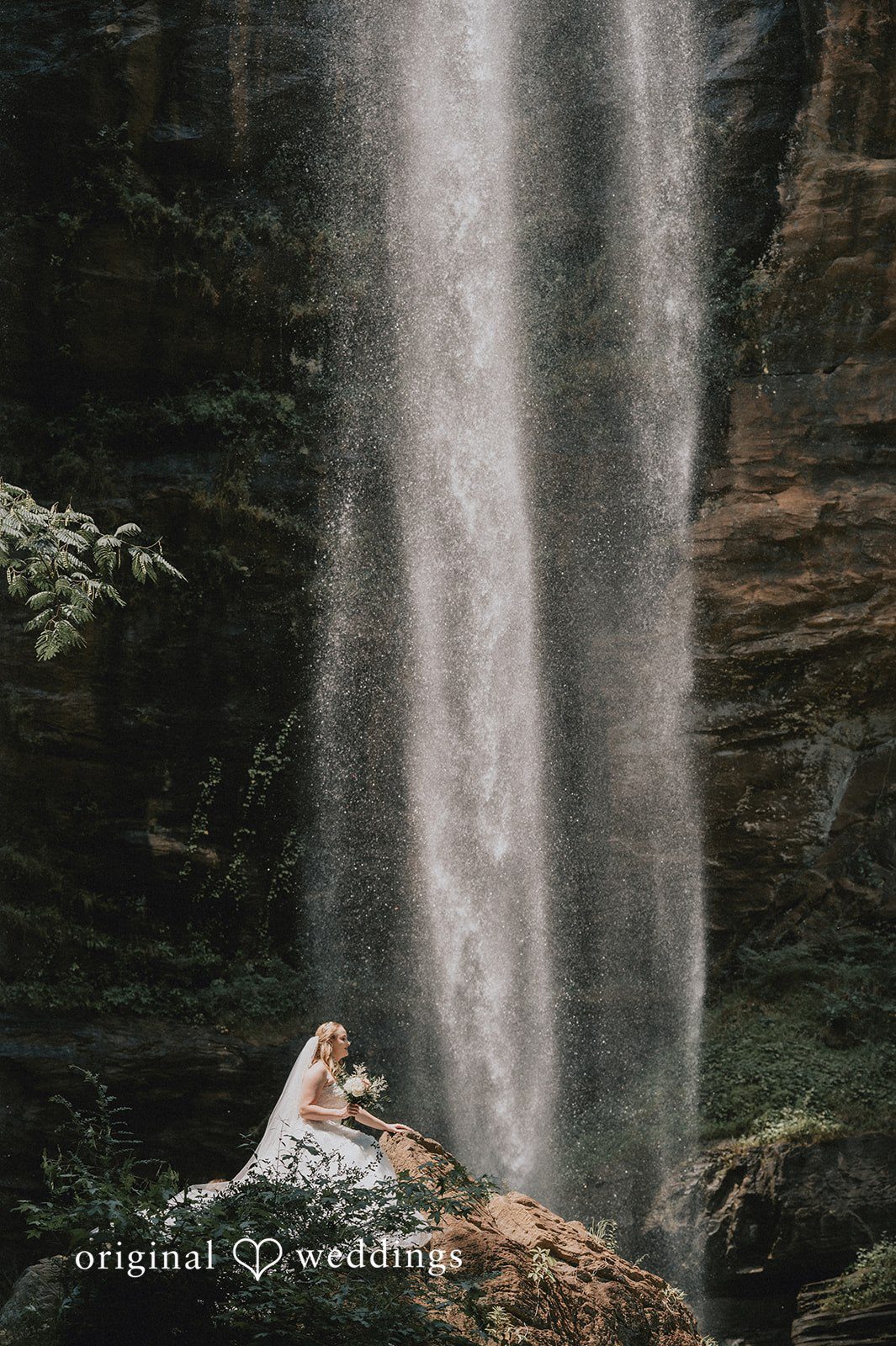 Sean + Hannah A wide shot of a powerful waterfall cascading down a tall dark cliff face.