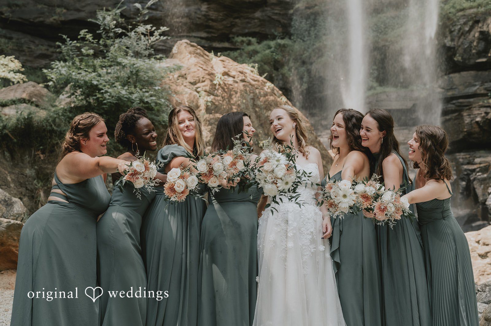Sean + Hannah A group of bridesmaids wearing dark olive gowns stand in a row holding bouquets.