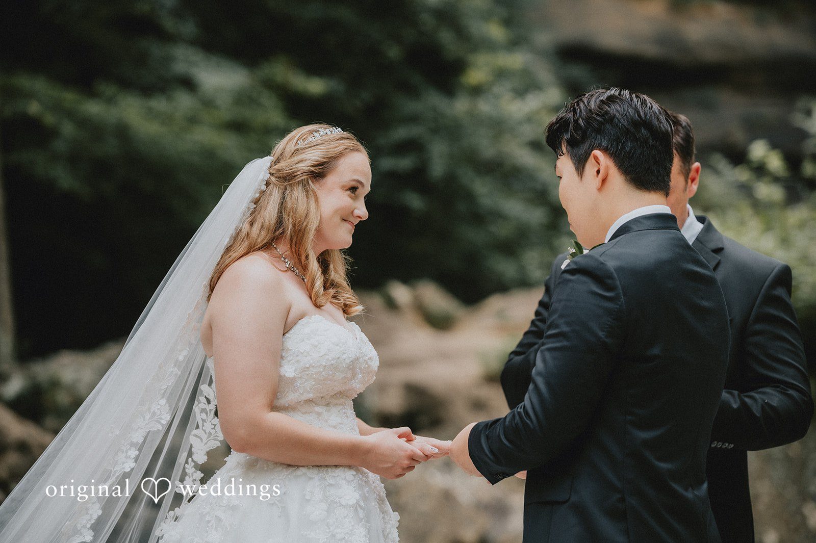 Sean + Hannah A bride and groom hold hands while facing each other during their wedding ceremony.