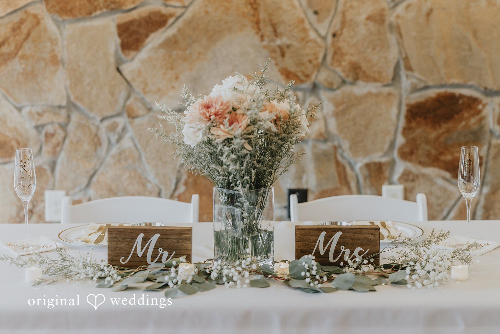 Sean + Hannah A floral centerpiece and table numbers set up on a rustic wooden reception table.
