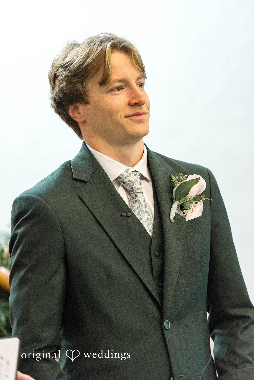 Groom in a green suit posing outdoors