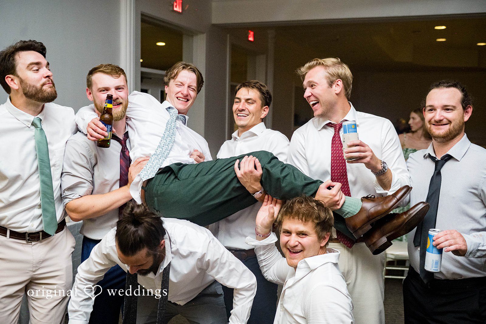 Groomsmen lifting the groom at the reception