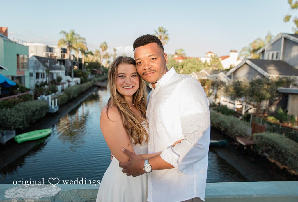 Christine and David smiling on a footbridge over the canal, captured by Engagement Photography Services from Original Weddings at Venice Canals