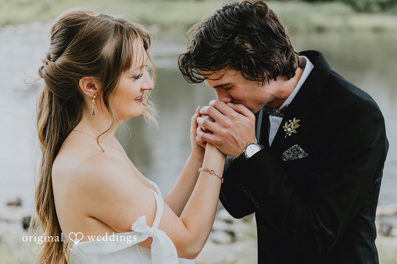 Grace + Andre Groom kissing the bride's hand by the water