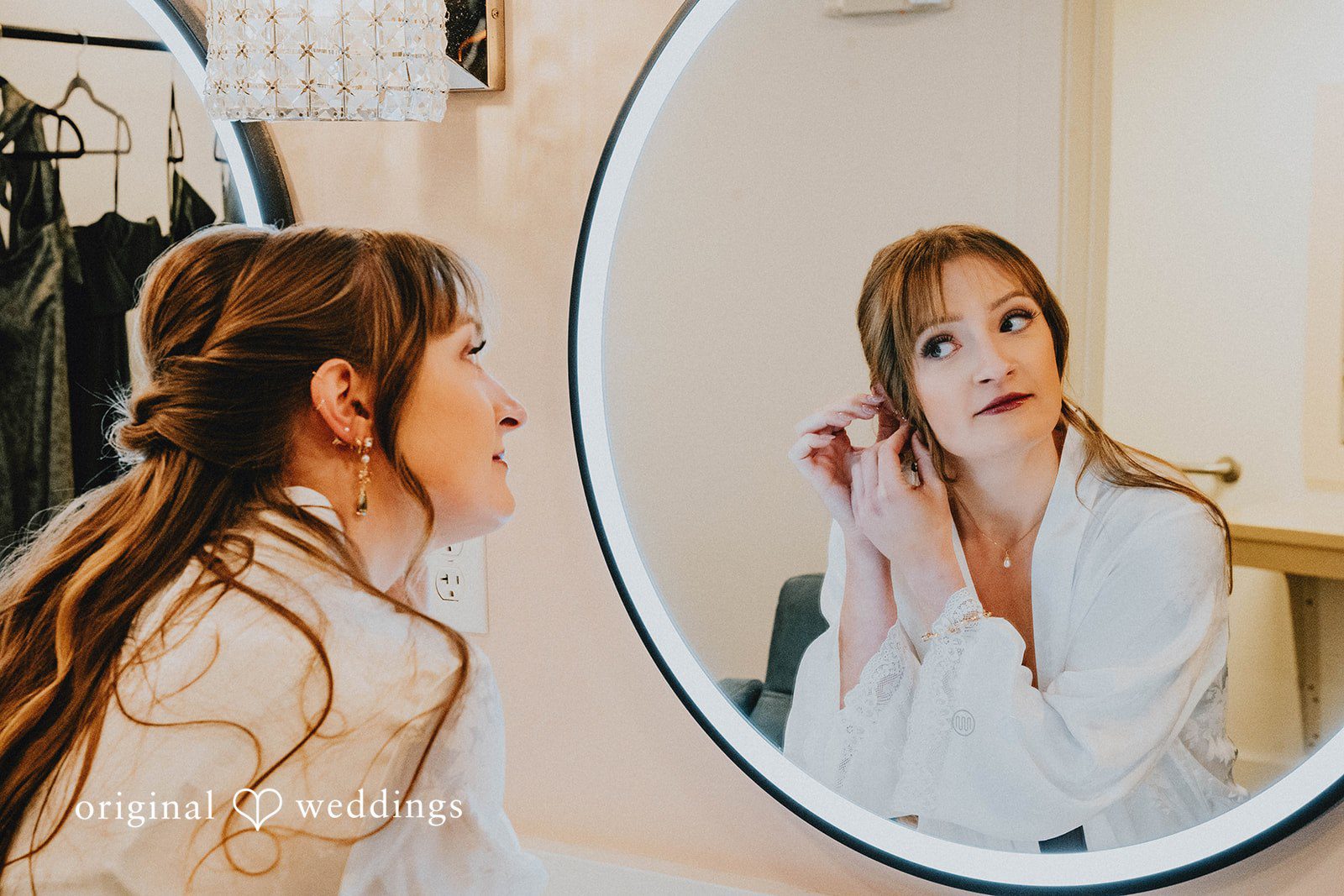 Grace + Andre Bride getting ready and smiling in a round mirror
