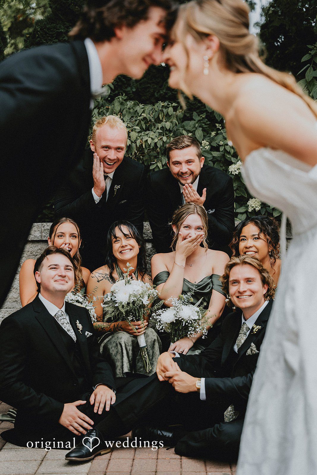 Grace + Andre Bride and groom touching foreheads as their wedding party smiles behind them