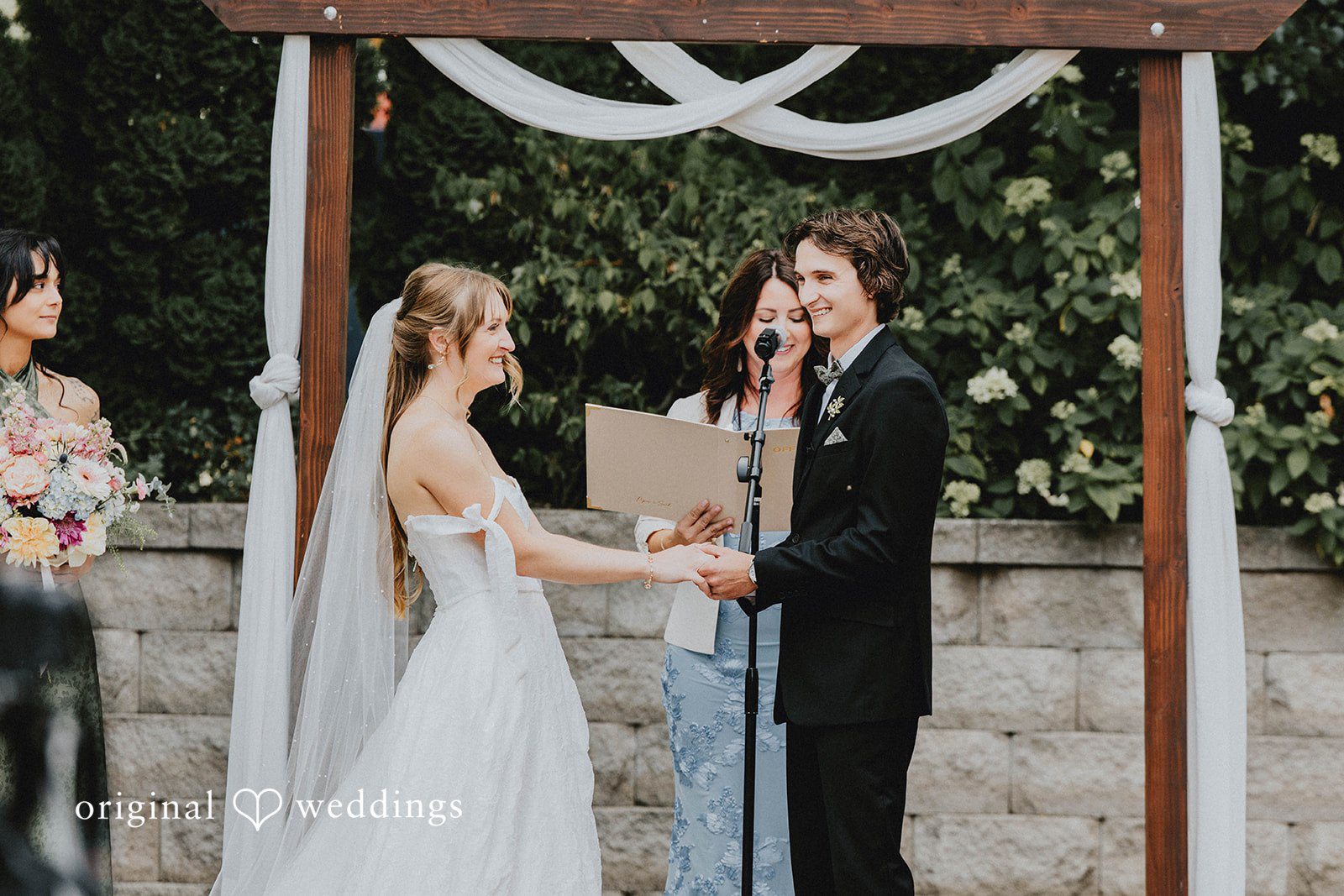 Grace + Andre Bride and groom exchanging vows under a draped arch