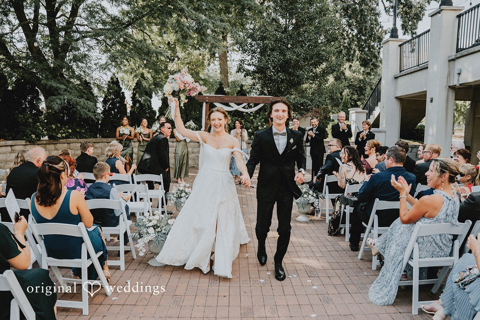 Grace + Andre Bride and groom walking up the outdoor aisle as guests celebrate at Veterans Terrace