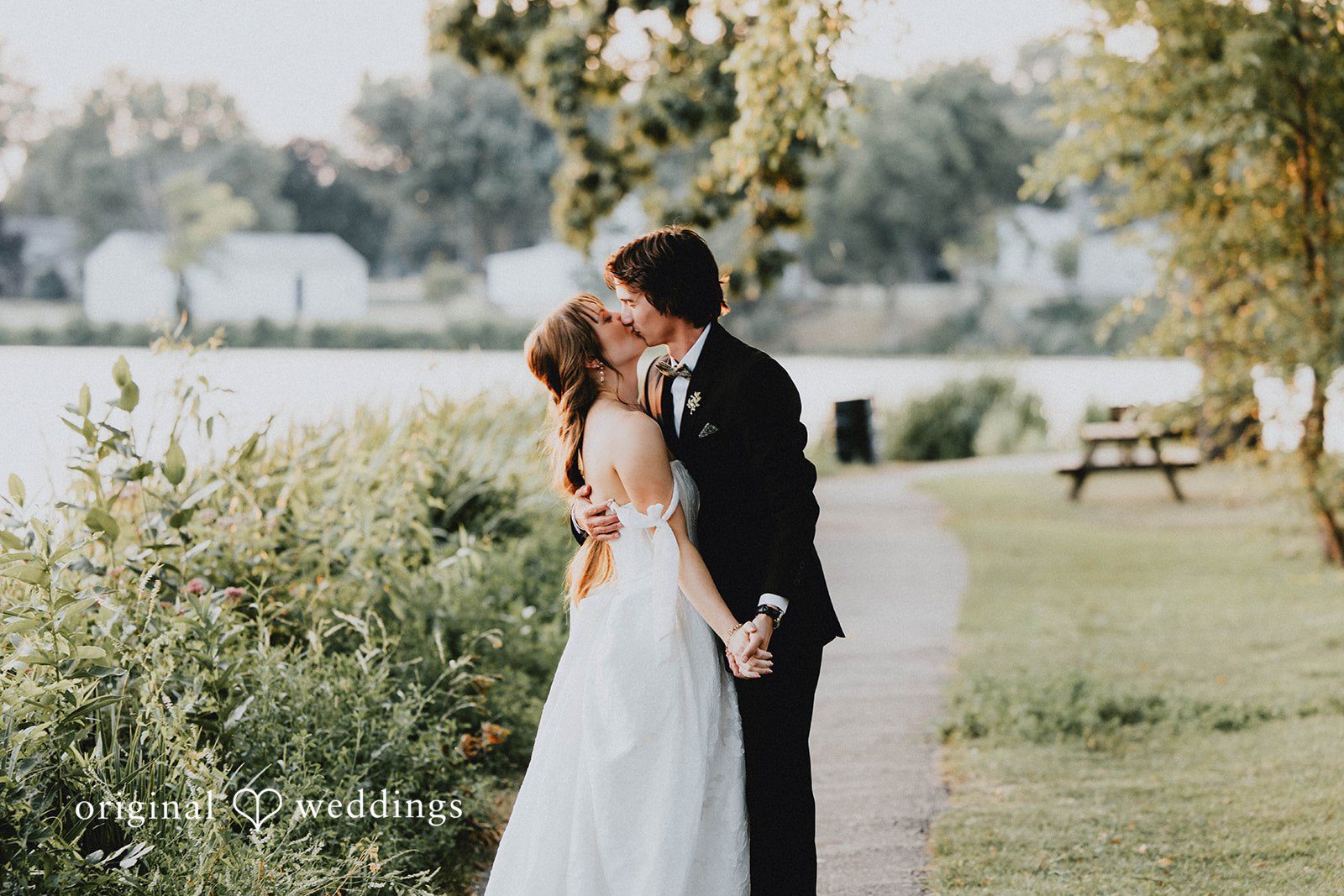 Grace + Andre Bride and groom embracing near the lake and flowers