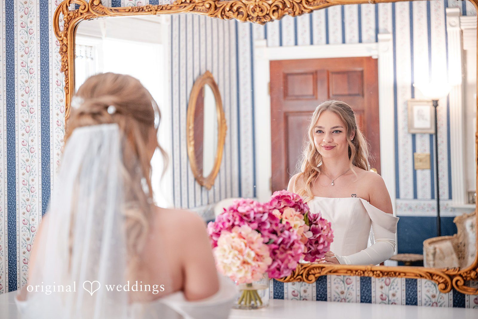 Kylie + Reymundo Bride getting ready by the mirror with flowers