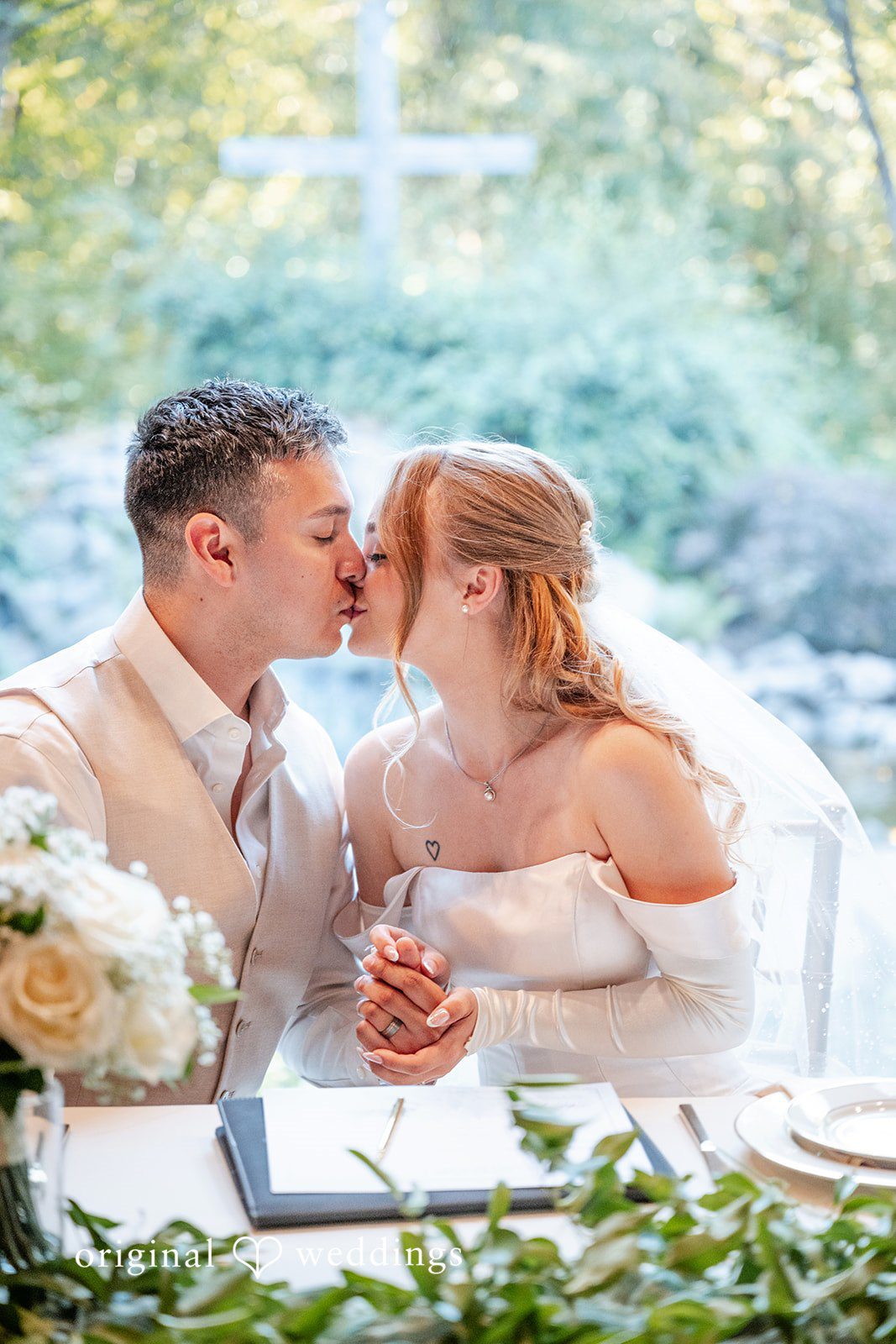 Kylie + Reymundo Couple sharing a kiss at the sweetheart table