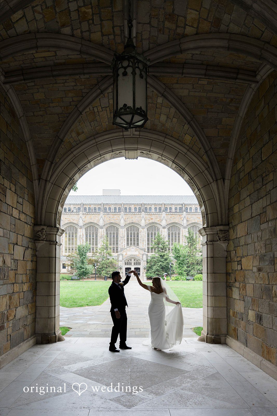 Bride and groom kissing under a stone archway, captured by Detroit wedding photographers from Original Weddings