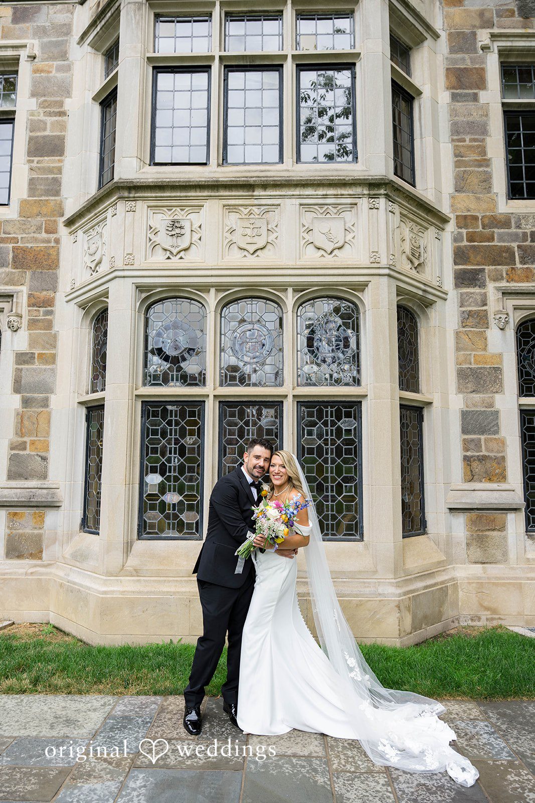 Bride and groom in front of tall stone windows