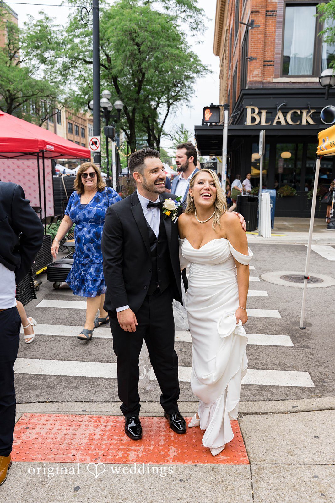 Andrew and Nicole walking down the street with wedding guests