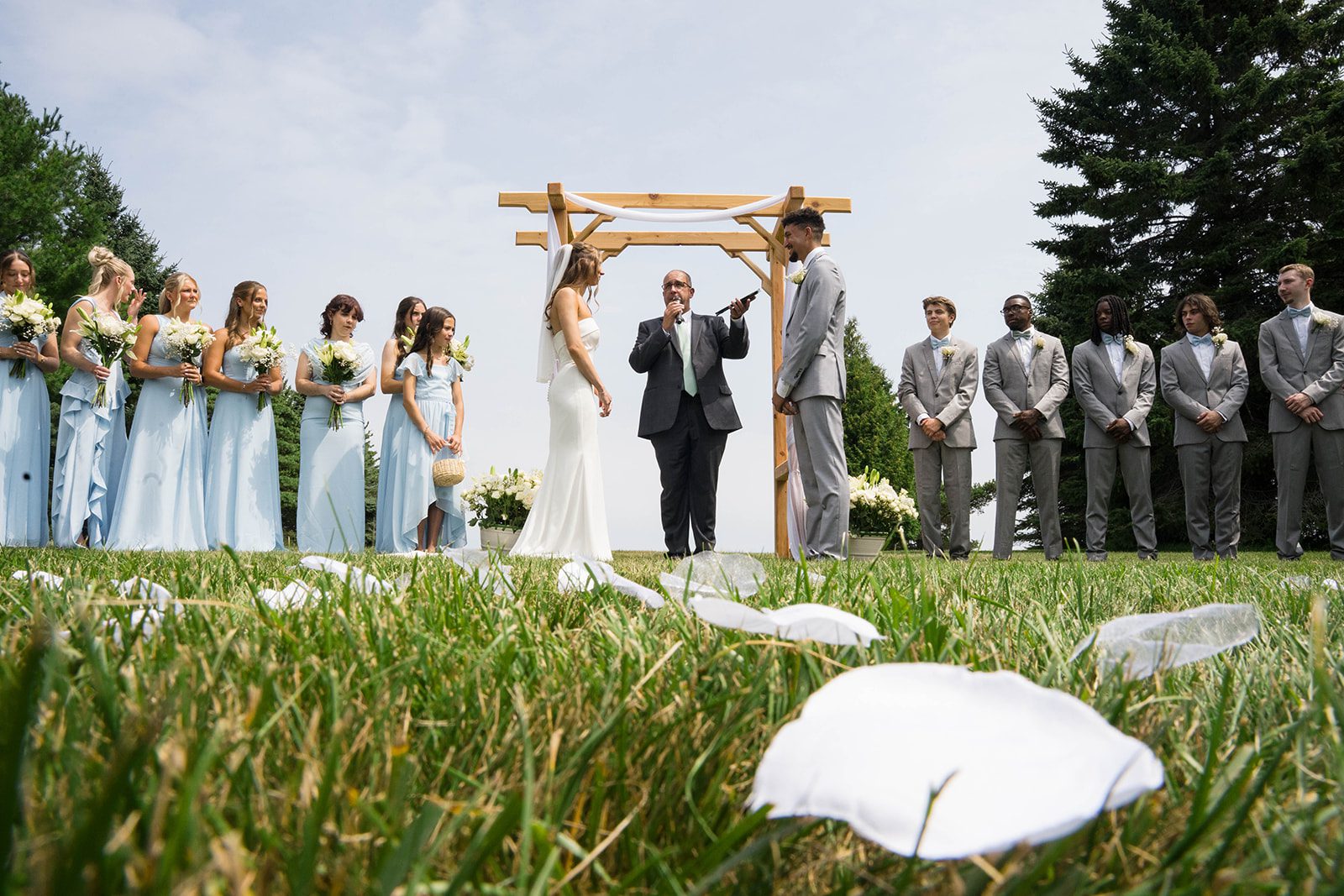 Couple at the wooden ceremony arch in the backyard
