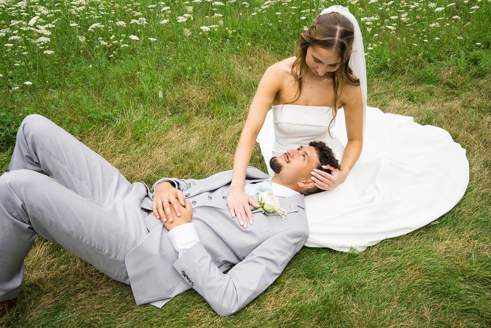 Bride and groom relaxing together in the grass, captured by Milwaukee wedding photographers from Original Weddings at their Wisconsin backyard wedding