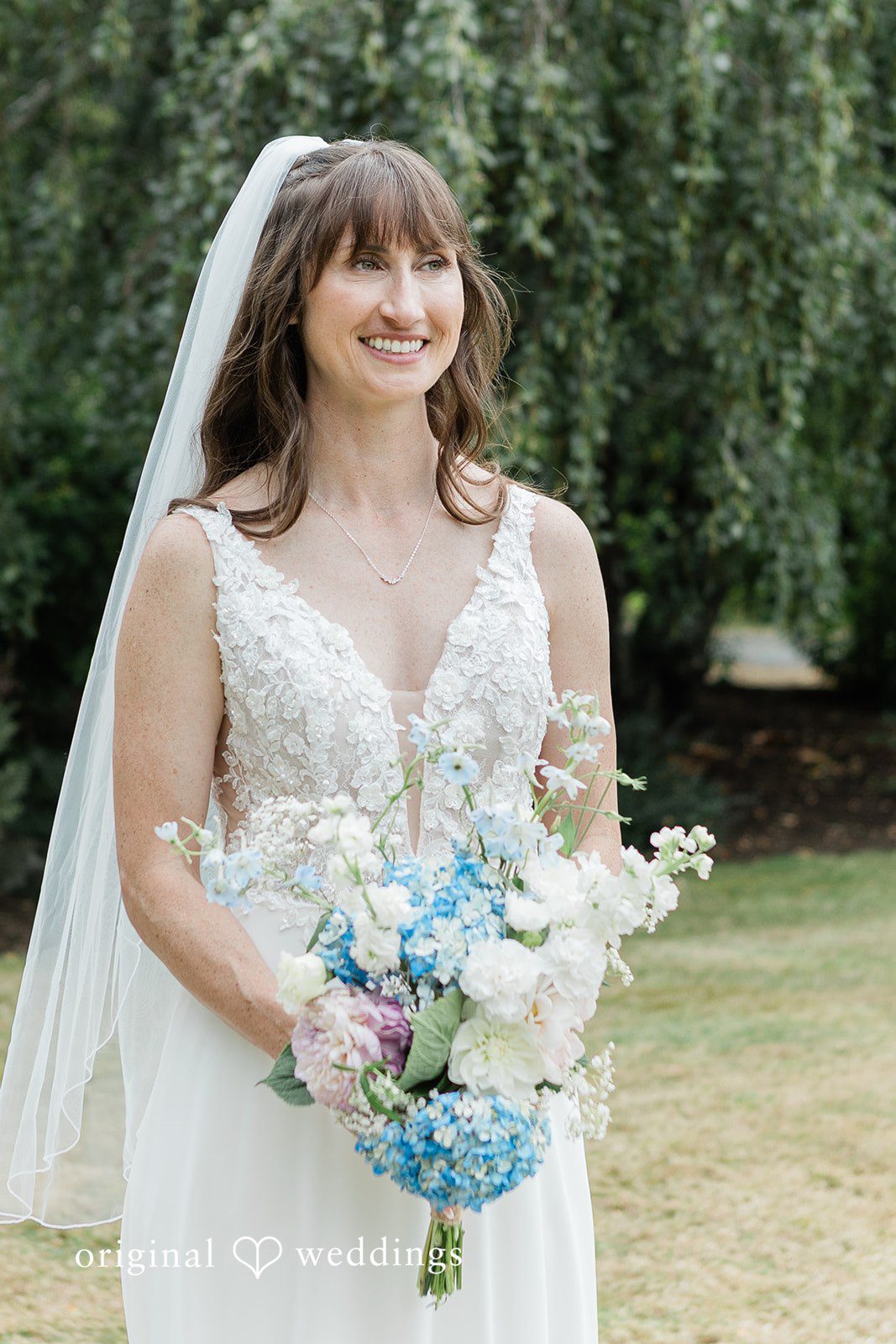 Rachel + Matt Bride holding her blue and white bouquet at Wisteria Gardens