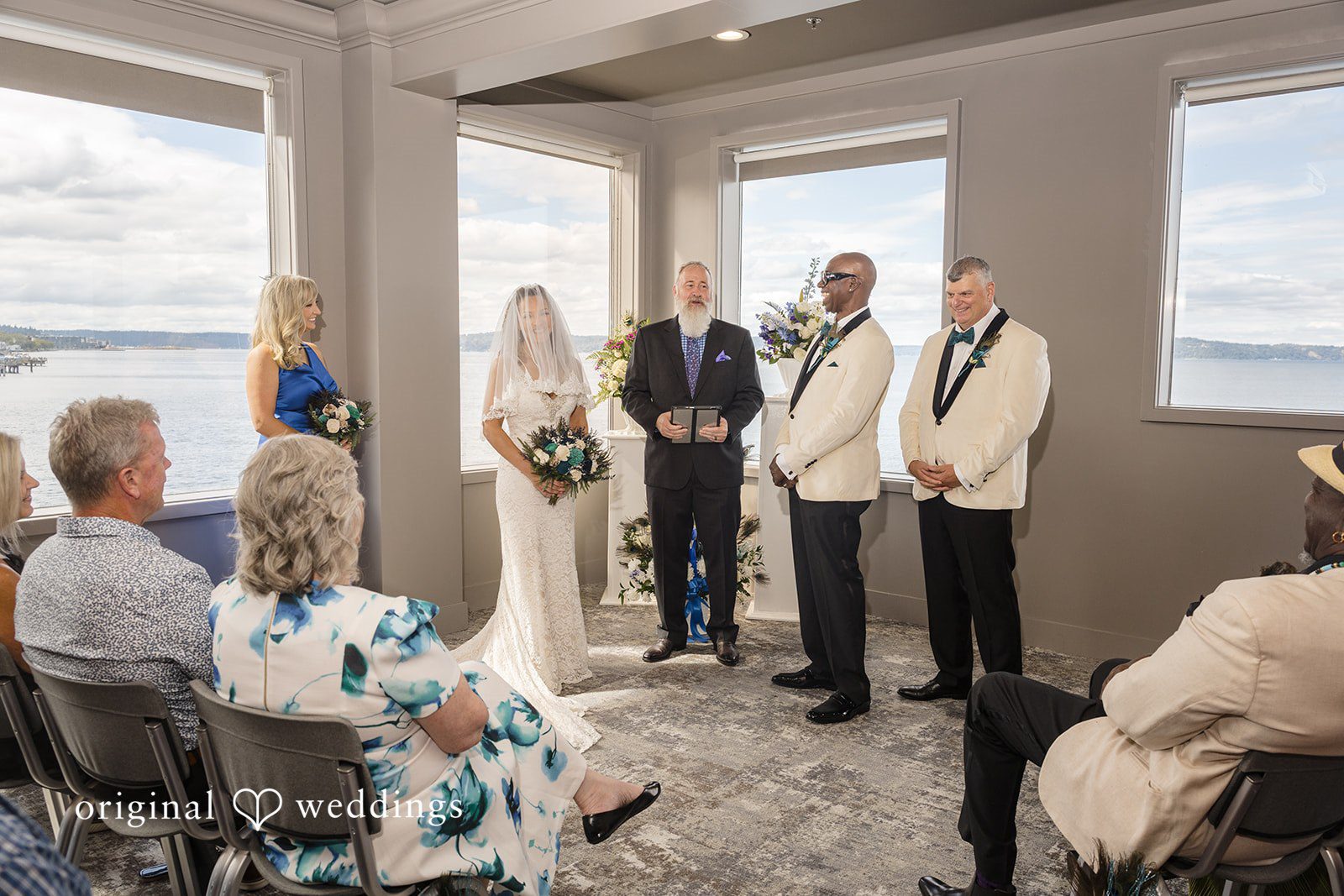Jennifer + Tony Seated wedding guests watching a ceremony inside a modern room with large windows.